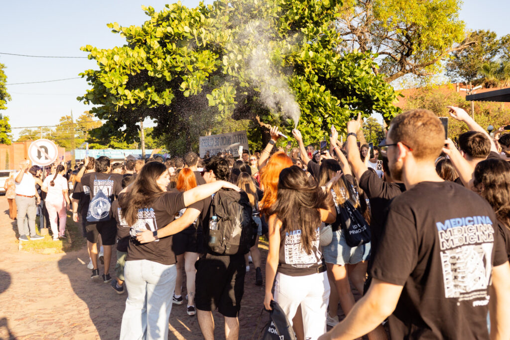 Estudiantes de la Facultad de Ciencias de la Salud celebrando su Último Primer Día (UPD) con carteles y distintivos de la carrera.